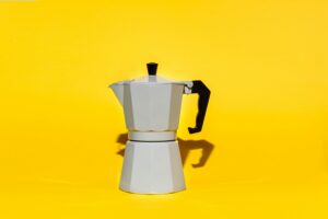 a stove top coffee maker on a yellow background